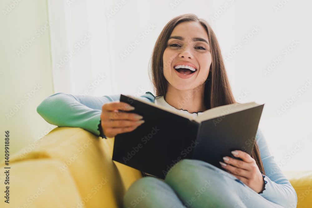 Young woman enjoying leisure time at home reading a book, expressing happiness and relaxation in a cozy indoor Young woman enjoying leisure time at home reading a book, expressing happiness and relaxation in a cozy indoor