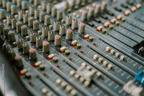 Close-up of professional audio mixing console surface with sliders knobs