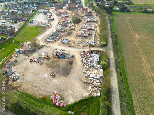 Obraz na płótnie Drone high altitude view of an expansive new housing development project in rural East Anglia. Homes seen in various stages of construction, the old village is on the left. w salonie