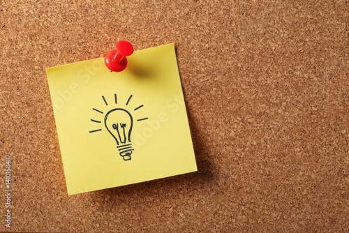 Yellow Post - it Note with Light Bulb Drawing, Pinned by Red Thumbtack on Corkboard.