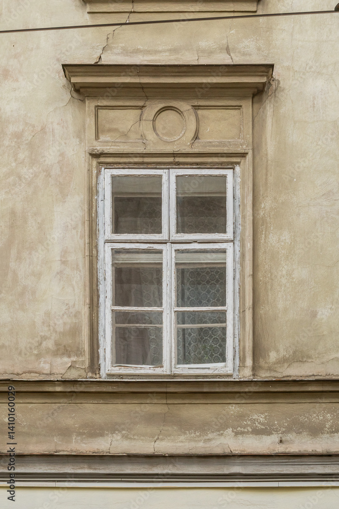 Old white wooden window with four sashes and classical stucco molding on aged beige facade. Old white wooden window with four sashes and classical stucco molding on aged beige facade.