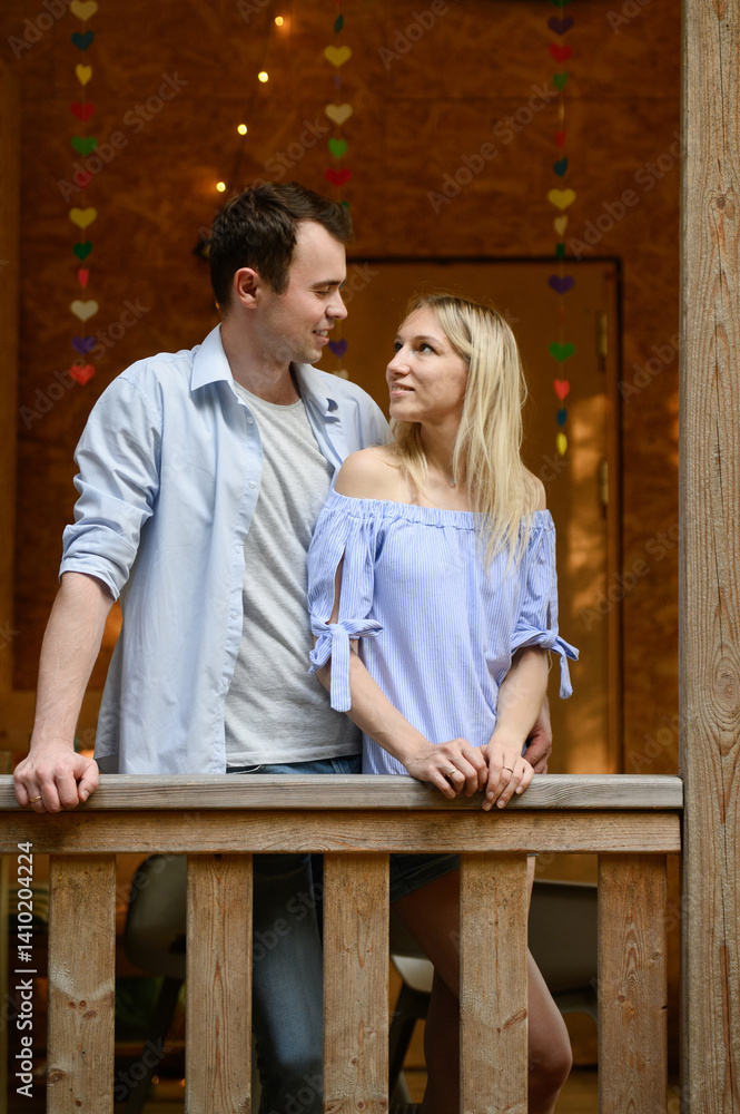 Man and woman standing on verandah of house, tenderly looking at each other, showing love and care. Couple in love in their own home. Concept of romance, dreams, rental housing Man and woman standing on verandah of house, tenderly looking at each other, showing love and care. Couple in love in their own home. Concept of romance, dreams, rental housing