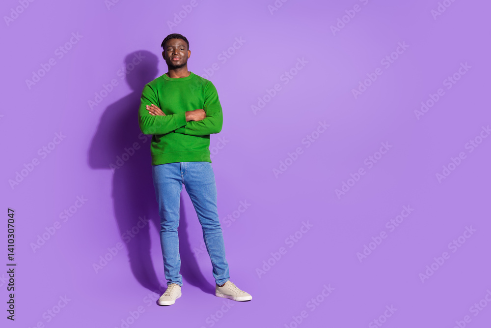 Portrait of a casually dressed young man wearing a green pullover standing confidently before a purple backdrop Portrait of a casually dressed young man wearing a green pullover standing confidently before a purple backdrop