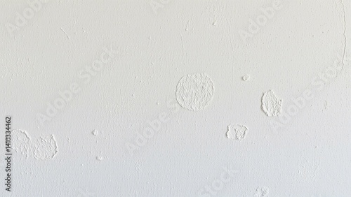 A close-up of a white wall with subtle imperfections, including small spots and minor blemishes. The image highlights the texture and minor inconsistencies in the paint, showcasing a raw, unpolished s