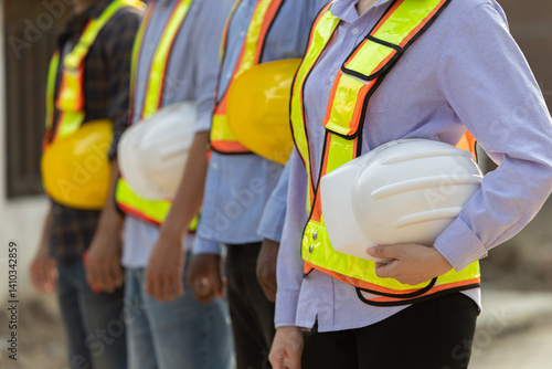 Team of construction workers in safety gear pose together at a building site