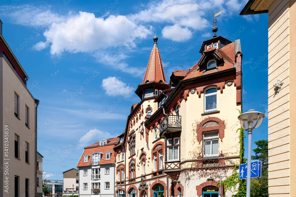 Historic residential buildings with ornate towers and red rooftops in the old town of Gotha, Thuringia under a bright blue sky