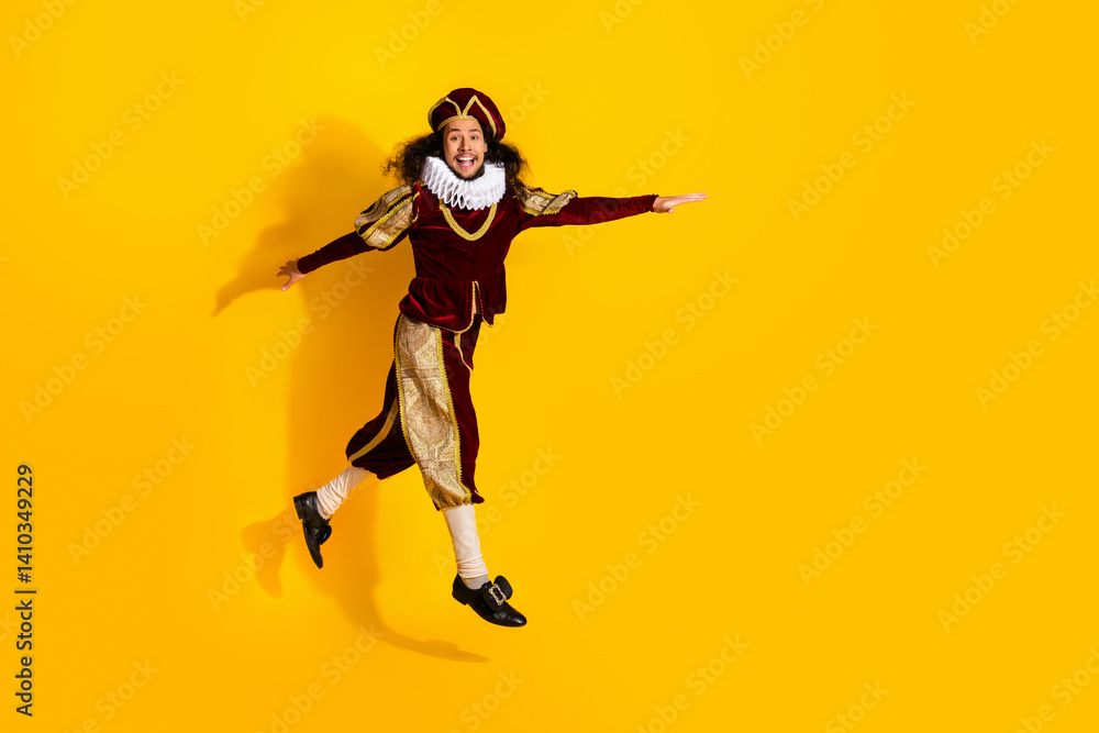Young man in medieval noble costume jumping joyfully on bright yellow background showcasing fun and elegance Young man in medieval noble costume jumping joyfully on bright yellow background showcasing fun and elegance