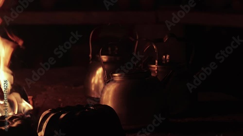 Flames of a fireplace wood fire in refuge hut, tea pot reflecting fire light