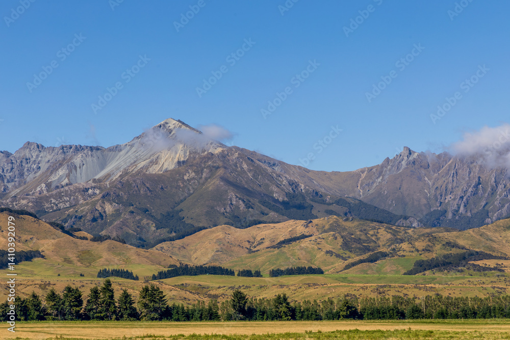 Beautiful rural landscape on highway 94. Mountain range, green fields, and forests. South Island, New Zealand