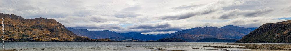 Lake Wanaka, a summer cloudy afternoon with a mountain range and the town of Wanaka on the shore. South Island, New Zealand