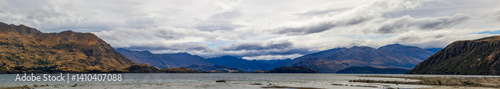 Obraz na płótnie Lake Wanaka, a summer cloudy afternoon with a mountain range and the town of Wanaka on the shore. South Island, New Zealand w salonie