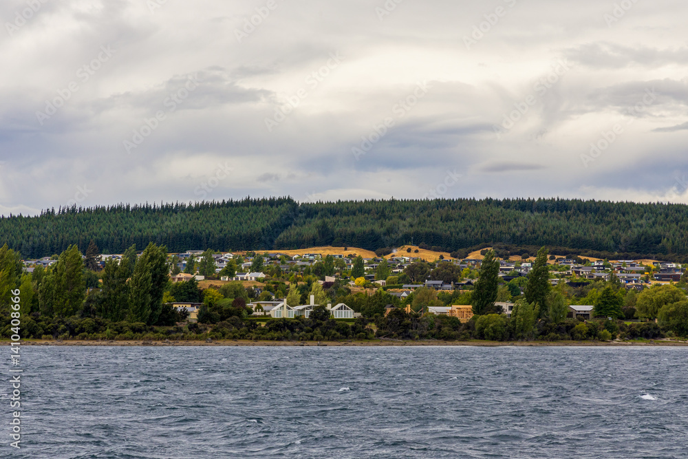 Lake Wanaka, a summer cloudy afternoon with a mountain range and the town of Wanaka on the shore. South Island, New Zealand