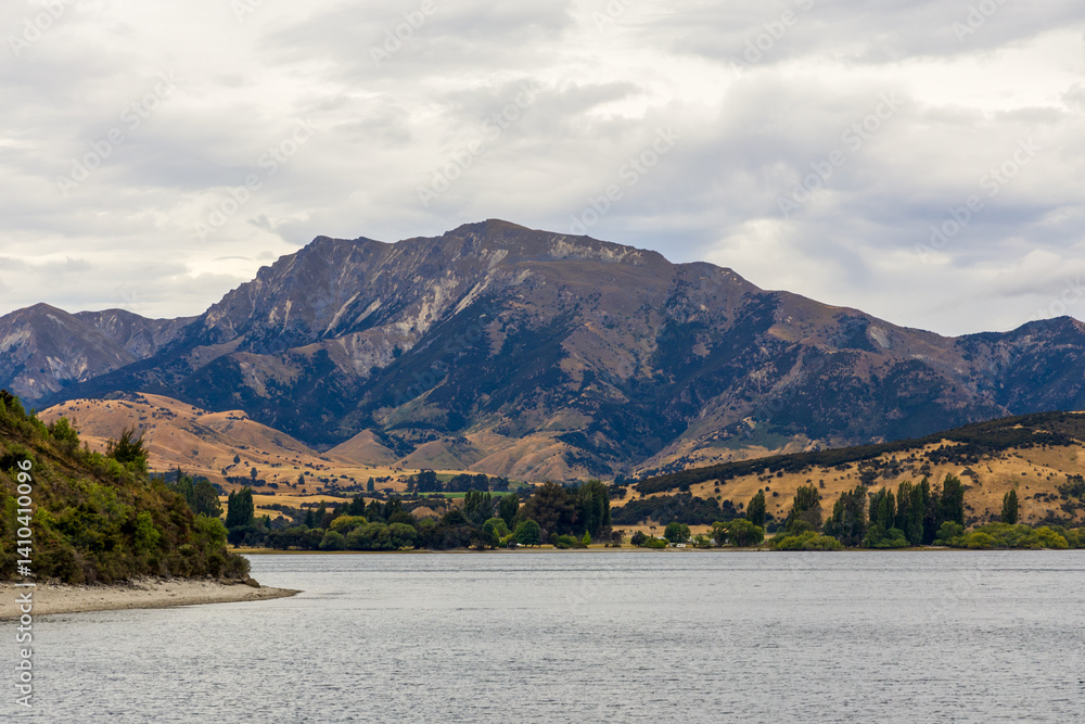 Lake Wanaka, a summer cloudy afternoon with a mountain range and the town of Wanaka on the shore. South Island, New Zealand