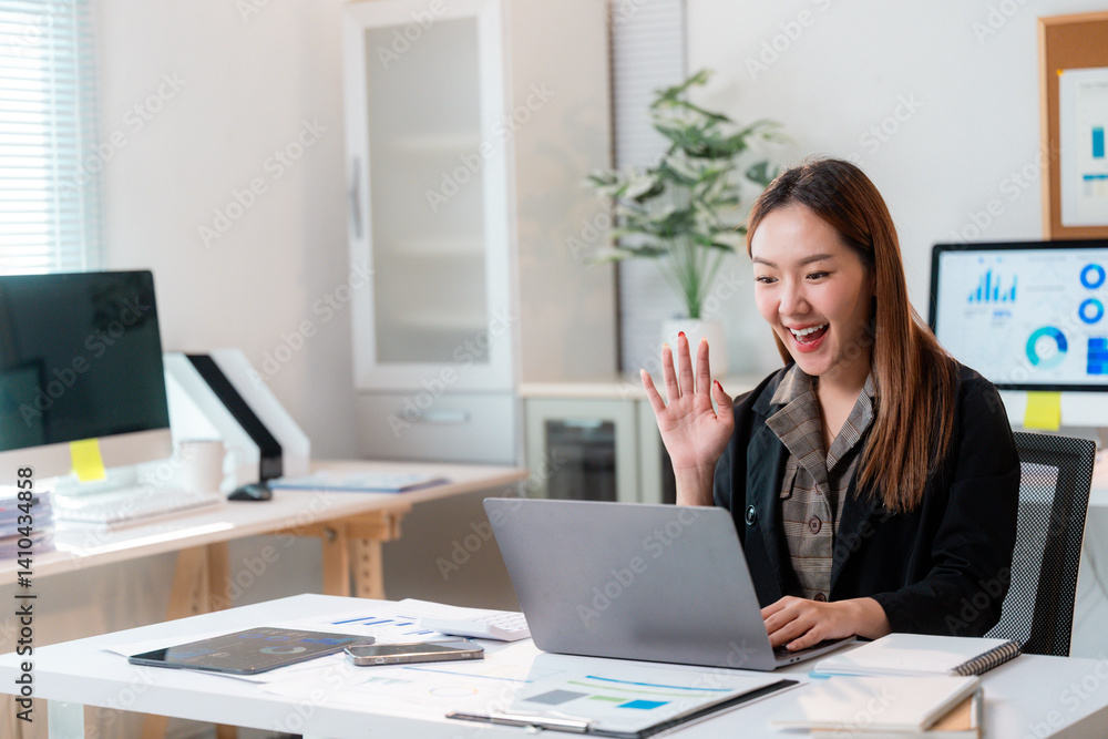 Smiling businesswoman waving during video call in office Smiling businesswoman waving during video call in office