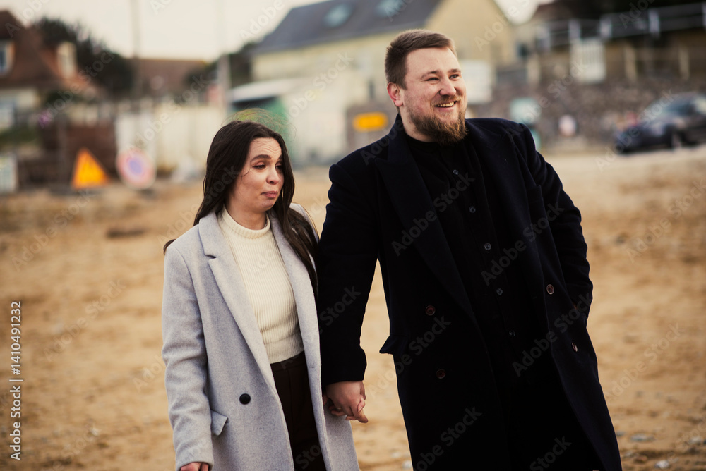Smiling caucasian couple walking on beach in winter Smiling caucasian couple walking on beach in winter