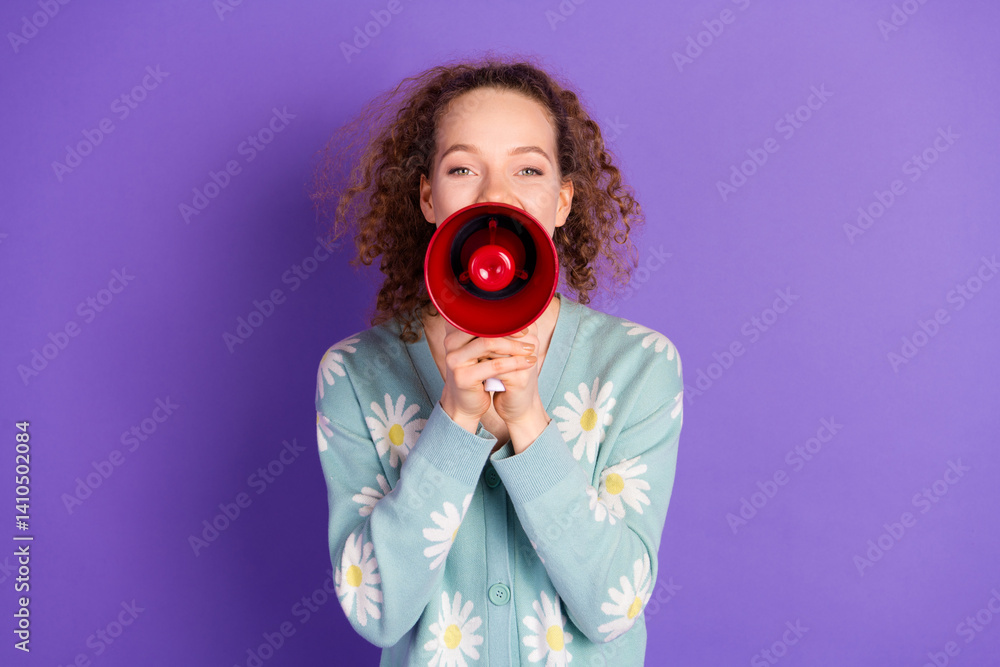 Obraz premium Young woman holding a red megaphone smiling on vibrant purple background wearing a flower patterned cardigan