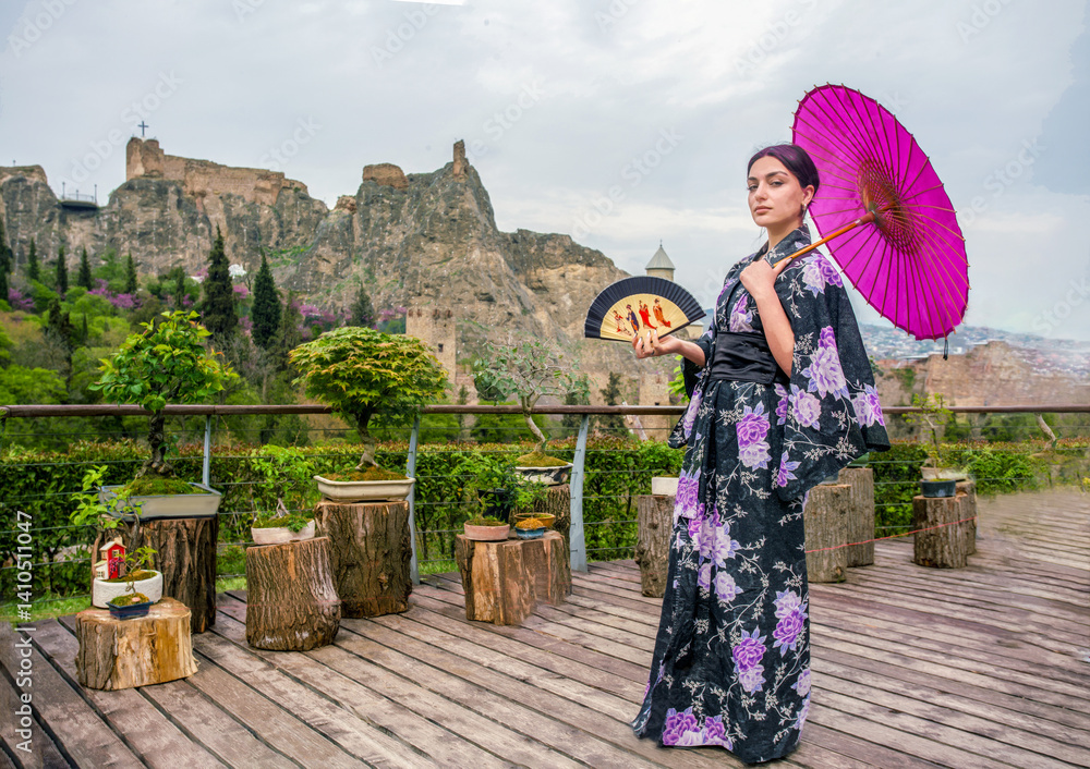 Beautiful young woman in Japanese kimono and close face with fan on holiday of cherry blossom
(look like Mona Lisa)