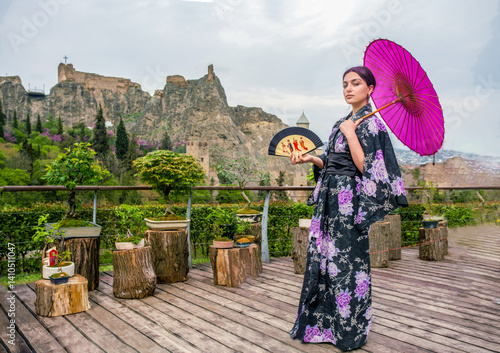 Obraz na płótnie Beautiful young woman in Japanese kimono and close face with fan on holiday of cherry blossom
(look like Mona Lisa) w salonie