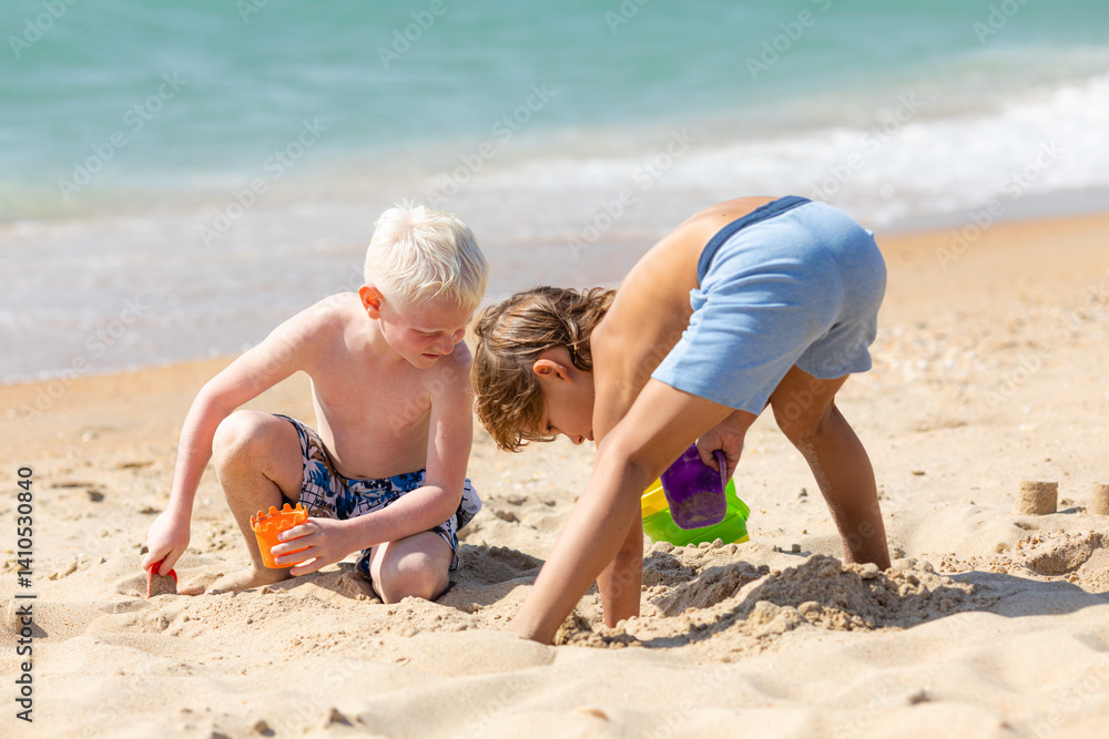 Children two little boys playing on the beach on summer holidays. Children have fun, build sand castle on the seashore. Vacation concept. Happy sunny day. Happy kids with ocean background. Copy space