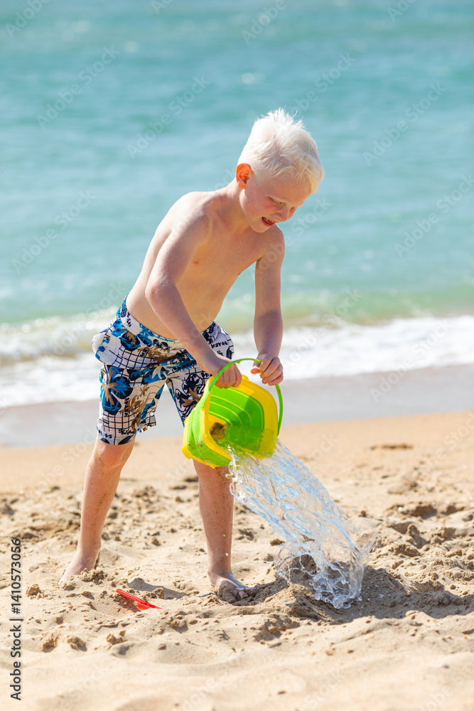 Happy little boy holding beach sand bucket. Concept of children beach summer vacation. High quality photo