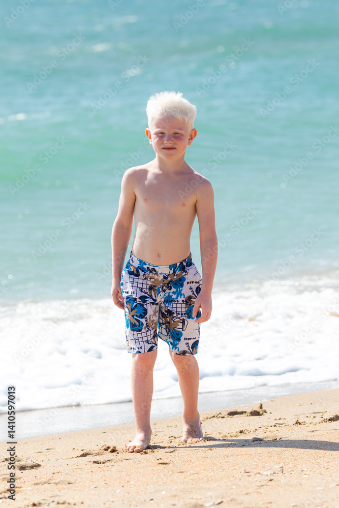 Cute little boy playing on the beach on summer holidays. Joyful child in nature with beautiful sea, sand and blue sky. Happy kid on vacation, walking on the beach and having fun