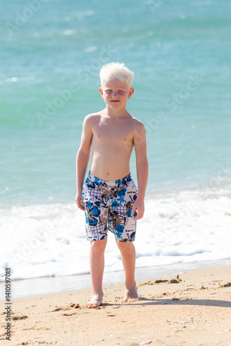 Obraz na płótnie Cute little boy playing on the beach on summer holidays. Joyful child in nature with beautiful sea, sand and blue sky. Happy kid on vacation, walking on the beach and having fun w salonie