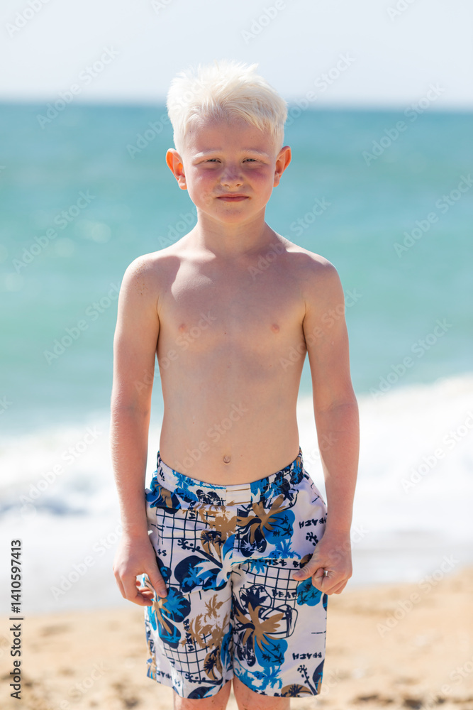 Cute little boy playing on the beach on summer holidays. Joyful child in nature with beautiful sea, sand and blue sky. Happy kid on vacation, walking on the beach and having fun