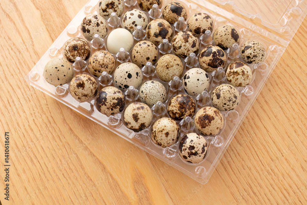 Speckled quail eggs in plastic container on wooden table
Speckled quail eggs in plastic container on wooden table