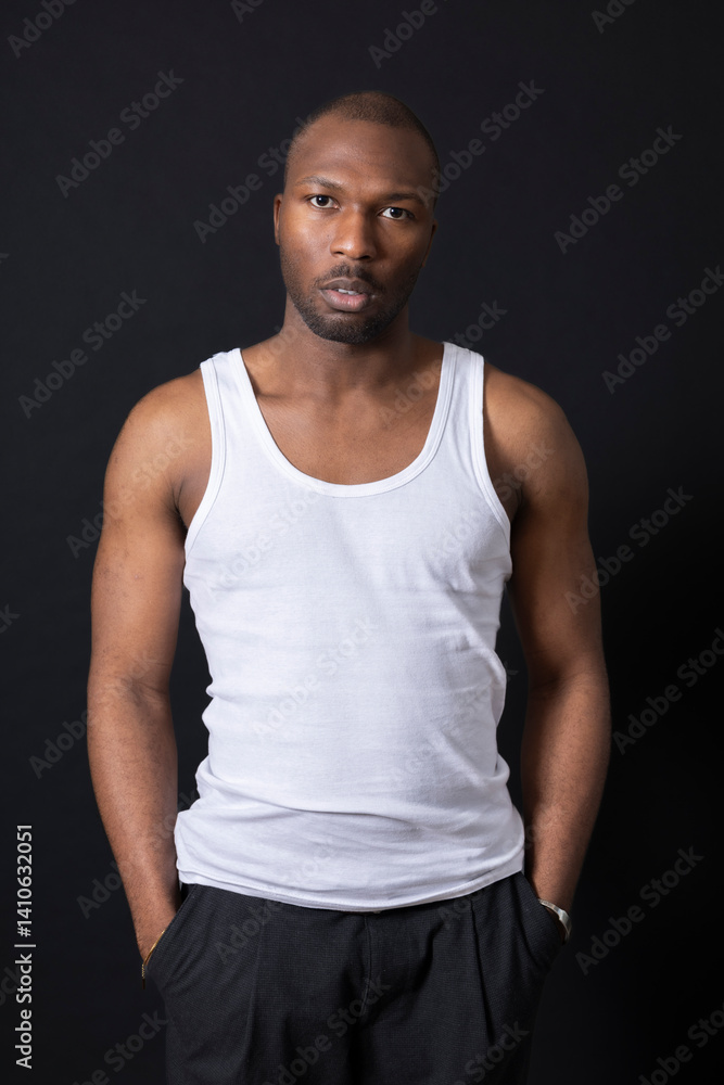 Portrait of a man in white tank top with hands in his pockets pose Portrait of a man in white tank top with hands in his pockets pose