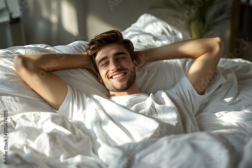 A relaxed man starts his day smiling in bed. Morning glow radiates through the bright bedroom.