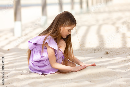 Obraz na płótnie Little cute child girl sitting on tropical beach and playing with sand, smiling on summer vacation. Happy children kid enjoy and has fun. Outdoor activity lifestyle on beach, holiday travel. w salonie