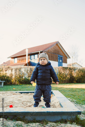 Obraz na płótnie Little boy in a jacket and hat on a spring walk on the playground. Child's walk outdoors. children's stylish spring clothes w salonie
