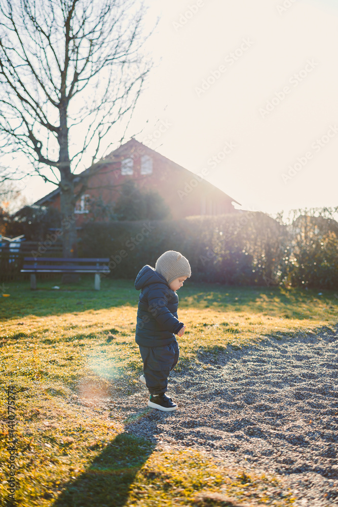 Little boy in a jacket and hat on a spring walk on the playground. Child's walk outdoors. children's stylish spring clothes