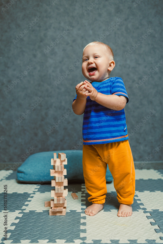One-year-old boy running around the nursery at home. Toddler boy in a T-shirt and pants playing with toys at home. Children's home clothes. Child's self-development at home.