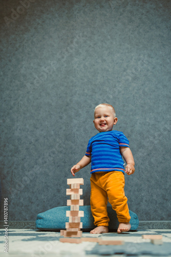 Obraz na płótnie A one-year-old boy at home in a t-shirt and pants is playing in the room. The child is having fun playing on his own. w salonie