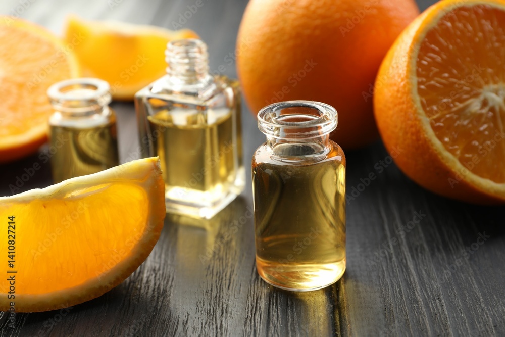 Open perfume bottles with aromatic essential oils and slices of oranges on black wooden table, closeup Open perfume bottles with aromatic essential oils and slices of oranges on black wooden table, closeup