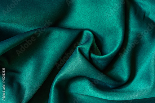 Blue green silk satin fabric. Teal color elegant background. Liquid wave or silk wavy folds. Beautiful dark turquoise background with copy space for your design
