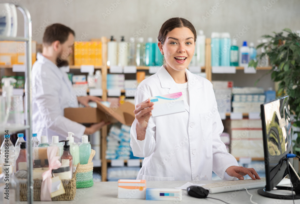 Female pharmacists using computer, remote document flow. Worker checks invoice and actual availability of drugs, checks incoming data on tablets. Assistant lays out pills merchandise in background Female pharmacists using computer, remote document flow. Worker checks invoice and actual availability of drugs, checks incoming data on tablets. Assistant lays out pills merchandise in background