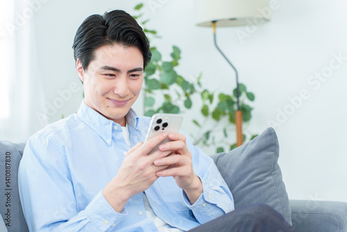 リビングでスマートフォンを使う男性