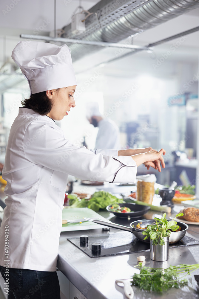 Young woman chef in restaurant kitchen carefully sprinkles fresh herbs onto a dish, enhancing the flavors with parsley, rosemary and basil. Modern workspace filled with fresh produce and spices. Young woman chef in restaurant kitchen carefully sprinkles fresh herbs onto a dish, enhancing the flavors with parsley, rosemary and basil. Modern workspace filled with fresh produce and spices.