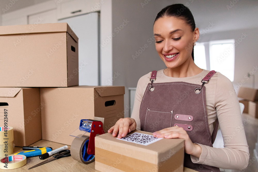 Happy woman entrepreneur putting barcode sticker on cardboard box, preparing parcels for delivery, working in warehouse office. Small business owner, e-commerce Happy woman entrepreneur putting barcode sticker on cardboard box, preparing parcels for delivery, working in warehouse office. Small business owner, e-commerce