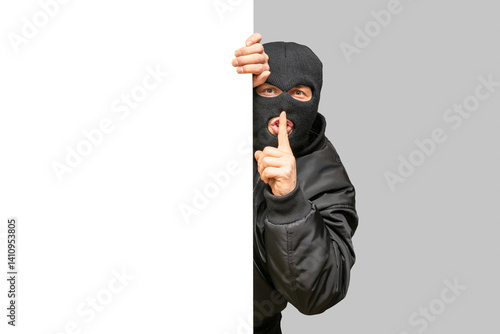 Thief hiding behind wall making silence gesture
