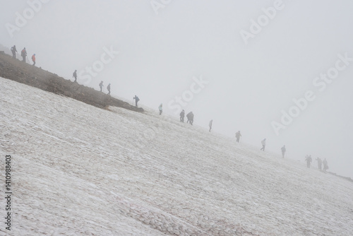 Obraz na płótnie Foggy mountain landscape. Hikers go down the snow-covered slope of the volcano. Low clouds, fog and poor visibility. Kamchatka Territory, Russia. Travel, tourism and hiking on the Kamchatka Peninsula. w salonie