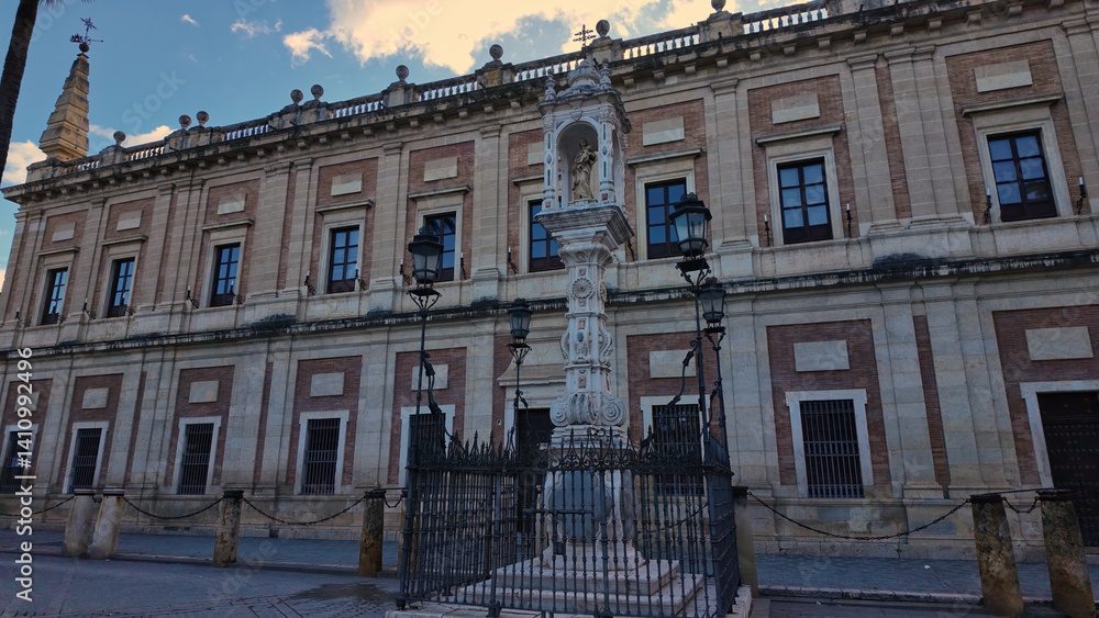 Obraz premium Archive of the Indies of Seville with statue and cloudy sky in the background