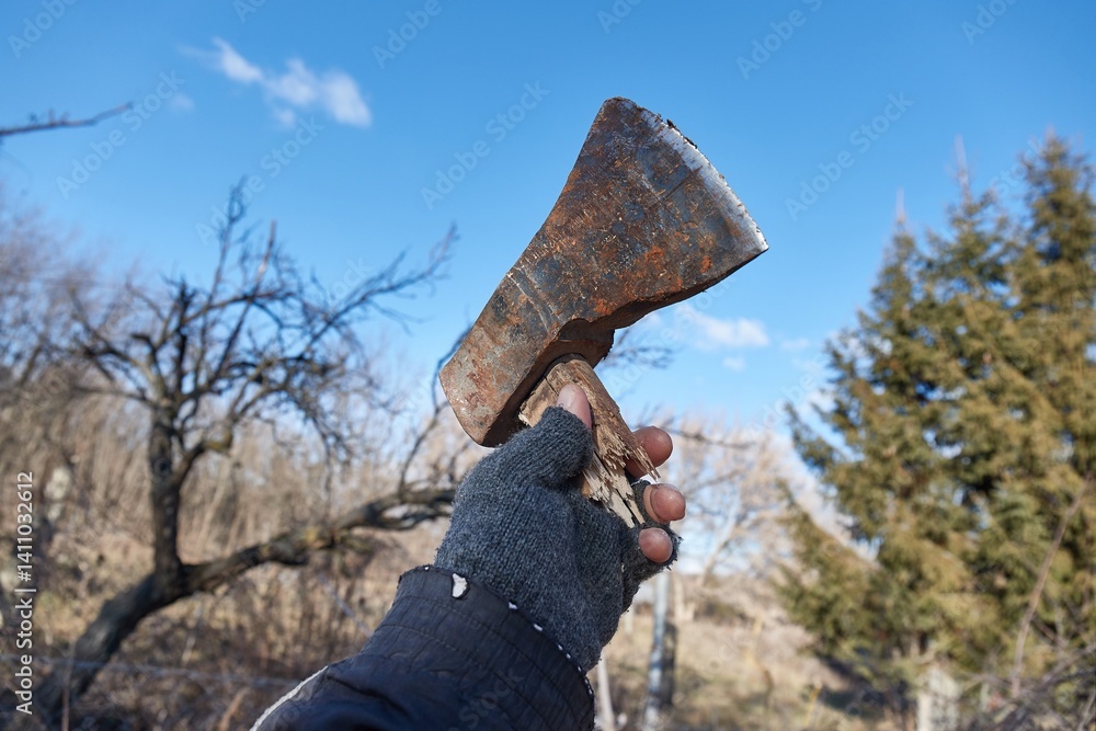 Broken axe held up in hand in the backyard