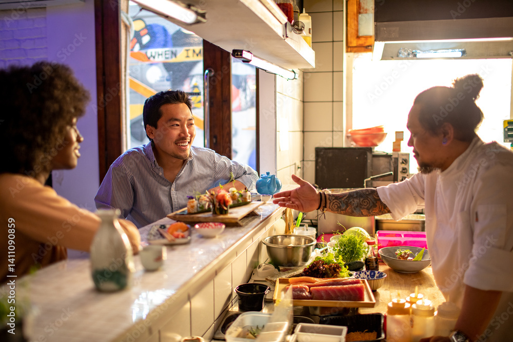 Friends chatting with sushi chef at restaurant counter Friends chatting with sushi chef at restaurant counter