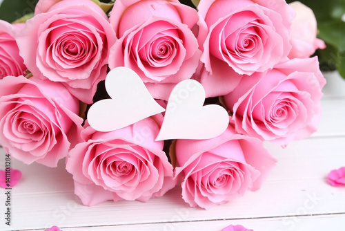 bouquet of pink roses with white hearts on a wooden table