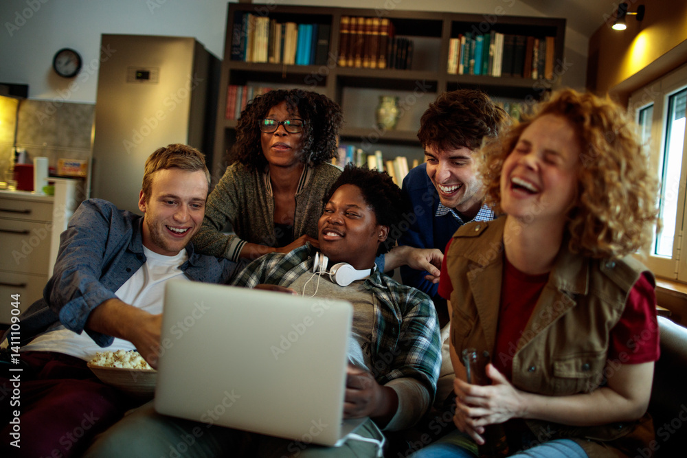 Obraz premium Young and diverse group of friends watching a movie on laptop in the living room on the couch