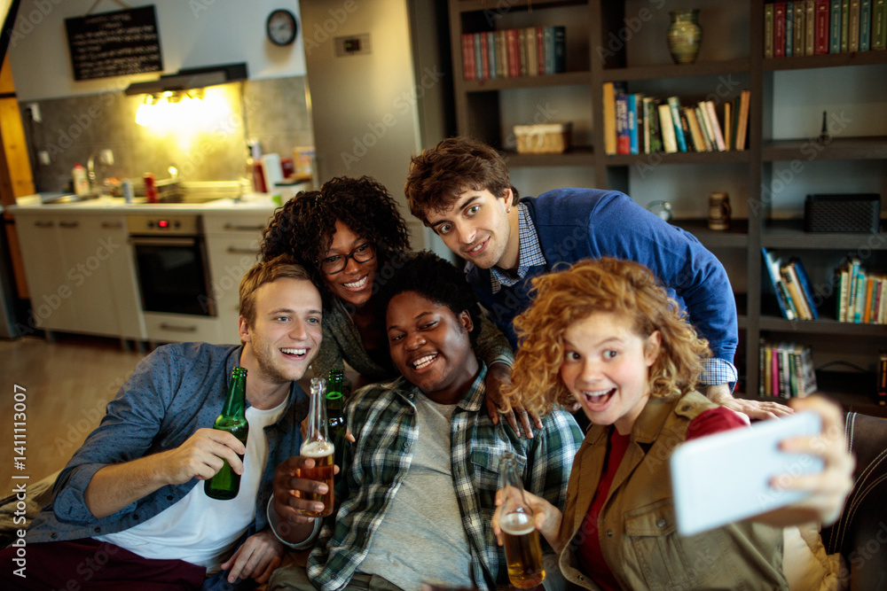 Young and diverse group of friends having a get together and taking selfies on a smartphone on the couch in the living room