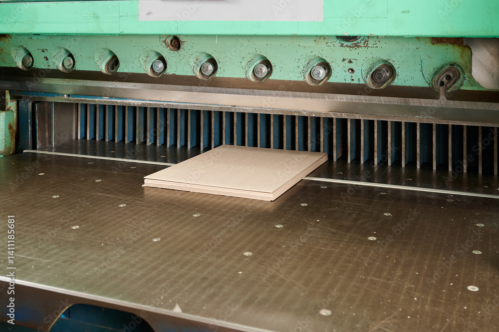 Precision crafting cardboard sheets on guillotine shears in a workshop setting during daylight hours Precision crafting cardboard sheets on guillotine shears in a workshop setting during daylight hours